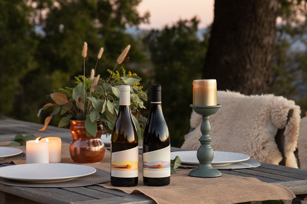 Two bottles of wine on a table with candles nearby