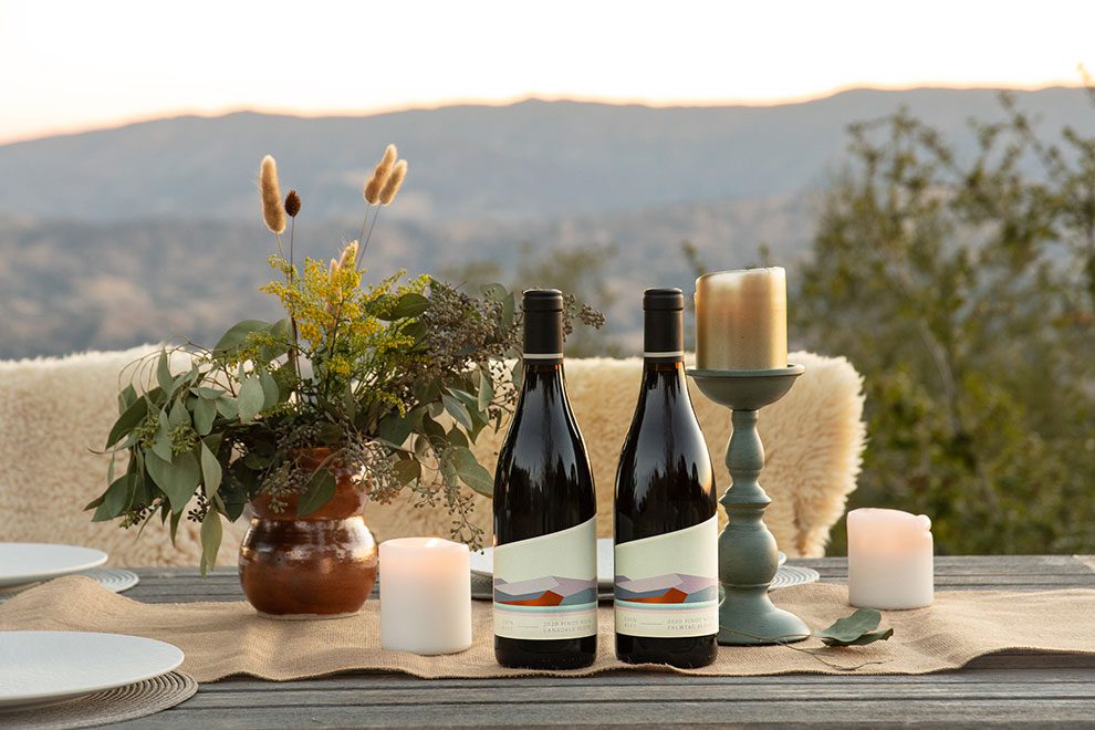 Two bottles of wine with candles and flowers on a table