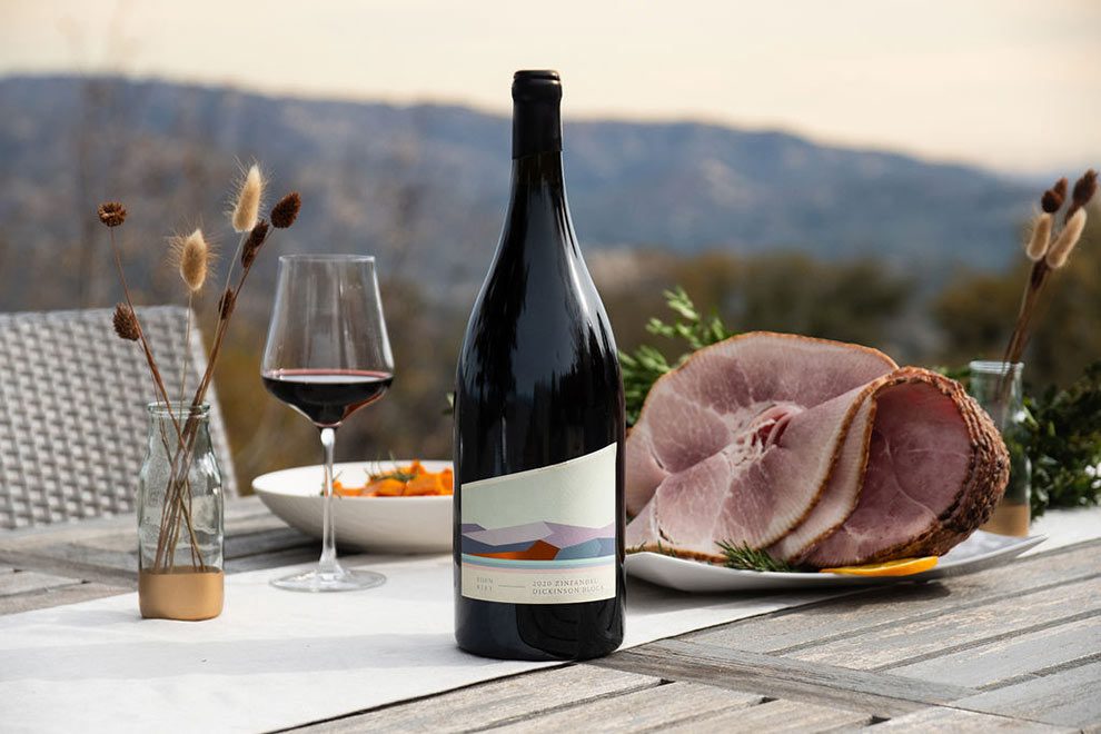 Zinfandel Magnum next to a sliced ham with a glass of wine next to it and hills in the background